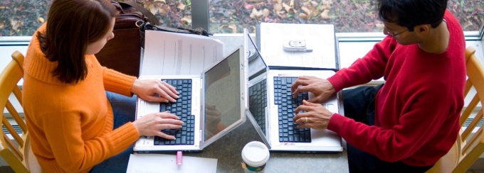 two students using computers and studying